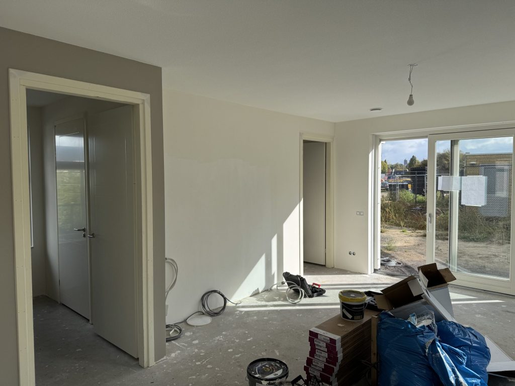 Woonkamer tijdens de klus met emmers en rollen behang klaar voor de behanger
