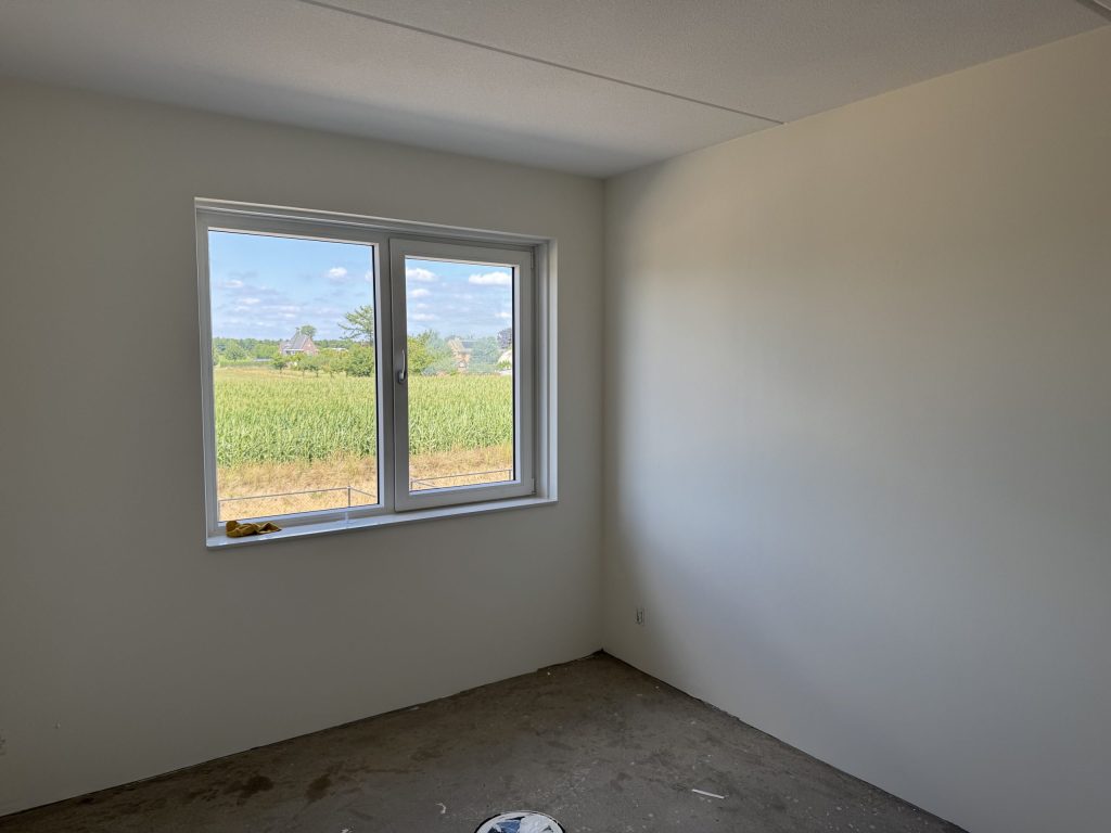 Slaapkamer met gladde witte wanden na het behangen en sauzen